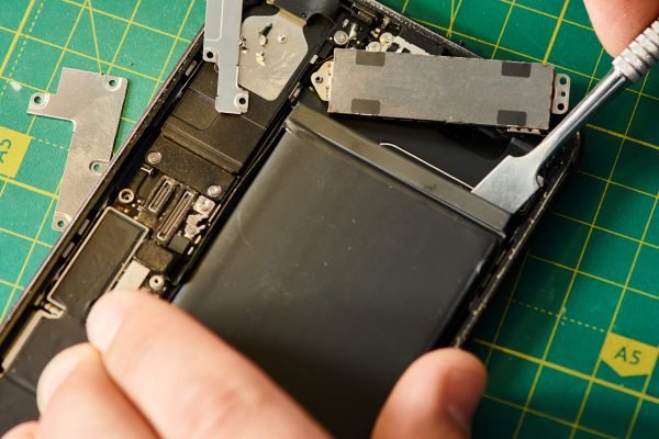 cropped view of technician opening smartphone during diagnostics in workshop, small business